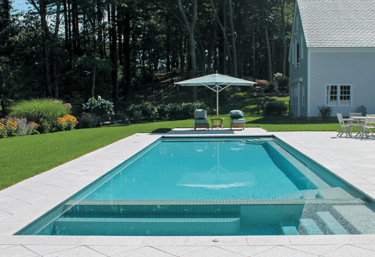 Rectangular pool with clear aqua water, light stone tiling and a shallow sun shelf for relaxed loung