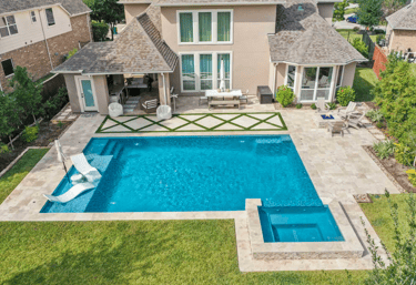 Large rectangular pool with bright blue water, light stone tiling and an attached square spa.