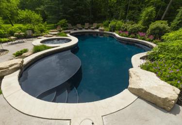 Freeform lagoon pool with dark teal water and light stone coping, paired with a curved built-in spa