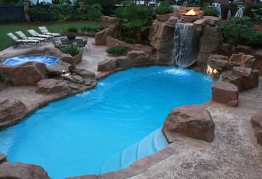 Curved lagoon pool with bright blue water, tan rock edging and light interior finish under warm ligh