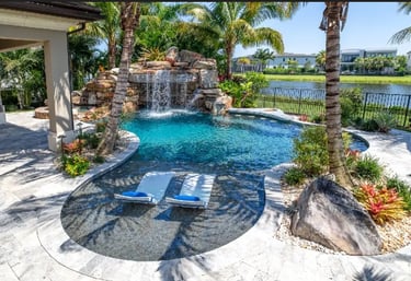 Freeform lagoon pool with aqua water, natural rock waterfall and light pebble interior creating a tr