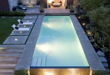 Long geometric pool with pale blue water and light stone tiling, giving a sleek modern minimalist lo