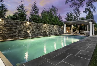Rectangular modern pool with soft aqua water, light beige coping and dark charcoal paving.