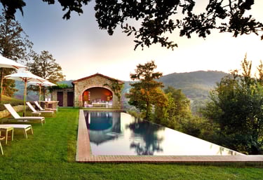 Infinity-edge pool with deep blue water and natural stone coping blending into the surrounding hills