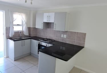 Modern small kitchen with black granite countertops, white cabinets, and gas stove stove.