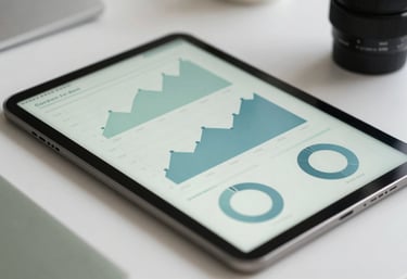 A clean, organized workspace showing a close-up of a tablet displaying analytical charts with Muted Sage and Pale Duck Egg Blue colors.