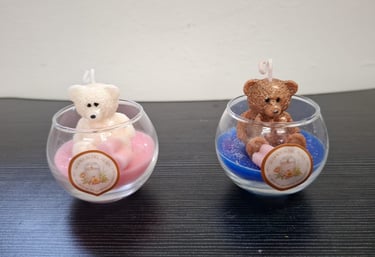 Handmade white and brown teddy bear candles in decorative glass jars with pink and blue wax.