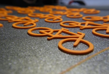 a bunch of orange 3d prints on our 3d printer buildplate