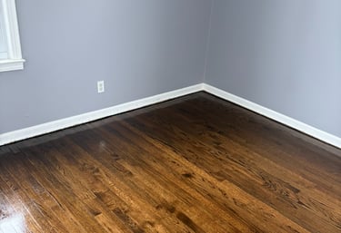 High Shine dark oak hardwood flooring in a room with light grey walls and white baseboards.