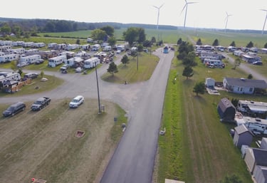 Aerial view of a spacious RV park and campground featuring paved roads and wind turbines.