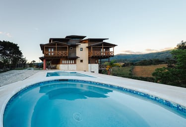 una villa de madera con piscina y una casa grande al fondo