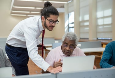 A younger man helping an older man with a computer