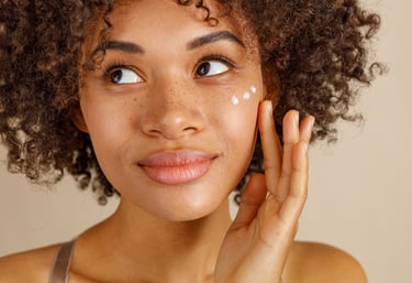 young woman applying moisturizer to face