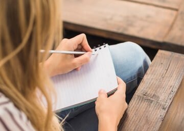 Personne prenant des notes dans un cahier.