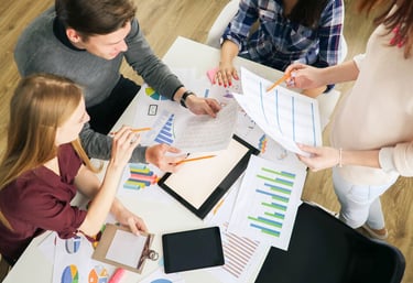Groupe de personnes discutant de graphiques et de documents lors d'une réunion.
