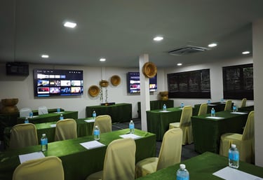a room with green tables and chairs and a television