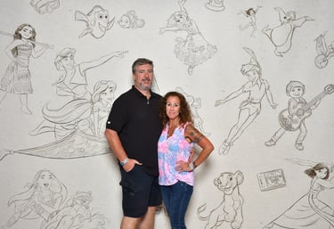 a man and woman standing in front of a wall with a mural of cartoon characters