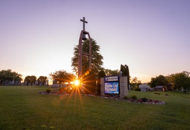 a church sign with a cross on the grass