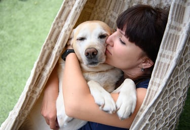 a woman is kissing a dog in a hammock