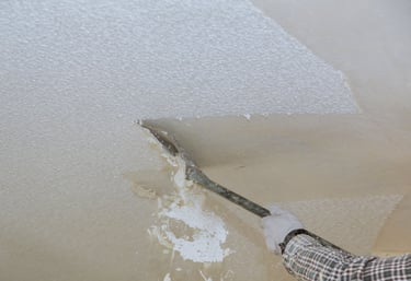 a person is holding a scraper removing Ceiling Texture
