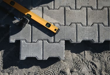 Close-up of interlocking concrete paver installation with leveling tools during a Sarasota driveway 