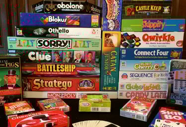 A wide selection of board games represented on a shelf.