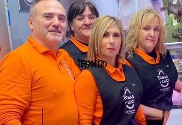 Empleados con protectores faciales y delantales en el mostrador de la carnicería Tomas y Luci.