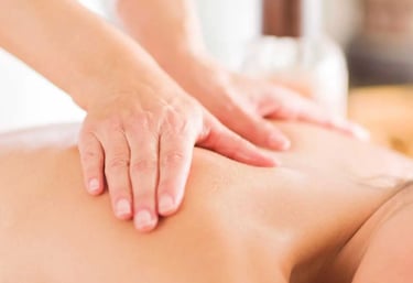 Close up of a massage therapist's hands applying pressure to a patient's back.