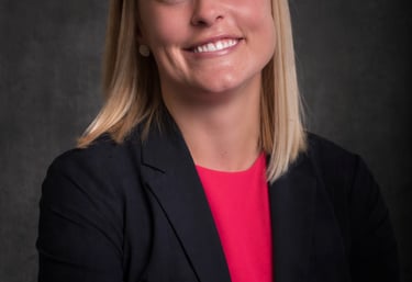 professional headshot of a woman in a black jacket and pink top