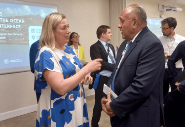 Filimon Manoni and Jutta Urpilainen are discussing in front of an IPOS presentation