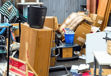 Trash, old furniture, and debris being picked up from a homeowners property.