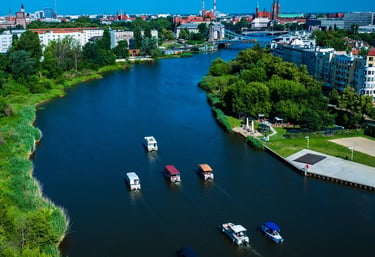 Aerial view of boats cruising the Oder River in Wroclaw, Poland with the city skyline and historic bridges.