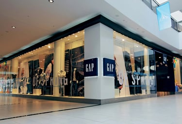 Drabužių parduotuvės vitrina prekybos centre su manekenais ir džinsais.