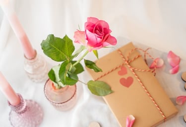 Pink rose in a vase next to a wrapped present