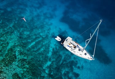 a sailboat in the water with a person swimming in the water