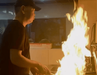 a man is cooking in a restaurant with a fire