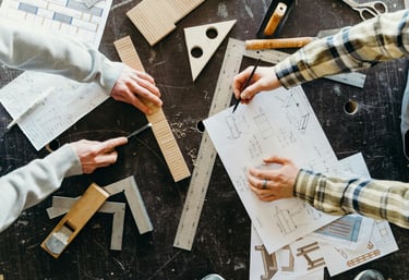 deux paires de mains travaillant sur des plans avec outils d'architecture