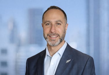 Arif Zaher headshot of a smiling businessman in a blue suit with a silver fern lapel pin.