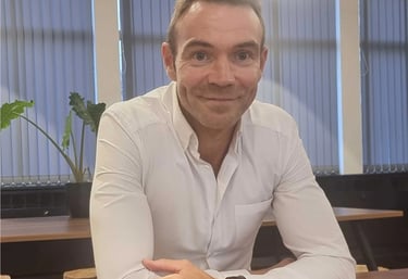 Man in a white shirt looks into the camera with a small smile
