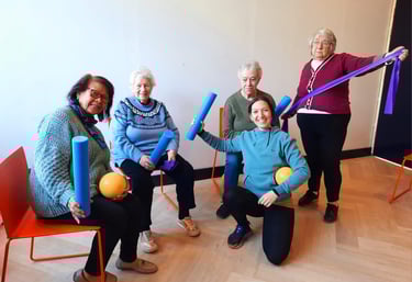 Groepsfoto van instructeur met oudere dames die poseren met materialen die gebruikt worden in de les