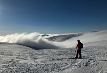 picture of one person viewing snowy fell landscape wiht clouds in valley and clear sky