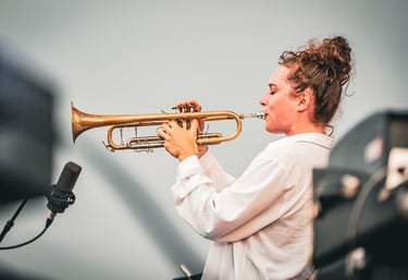 une femme en chemise blanche et trompette au Festival de Jazz de Saint-Omer