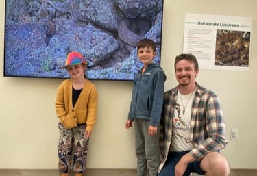 Project Rattlecam Team member, Owen, and 2 kids in front of RattleCam Zoo display