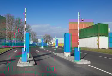 Automated gate system at sea port with barriers and container yard in background.