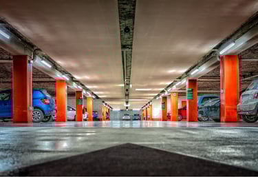 Underground parking lot with orange columns and smart lighting under surveillance system.