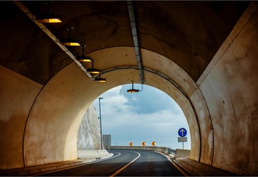 Inside view of a modern road tunnel with lighting and exit signage for smart monitoring and evacuation control.