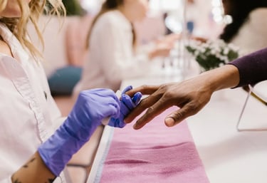 a woman is getting her nails done by a professional wearing gloves.
