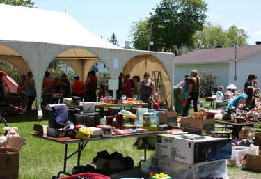 a group of people standing around a table with many items
