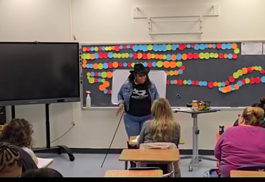 A teacher wearing a cowboy hat leads an interactive classroom presentation for adult learners.