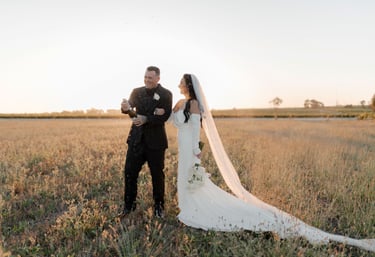 a bride and groom popping a champagne bottle at sunset